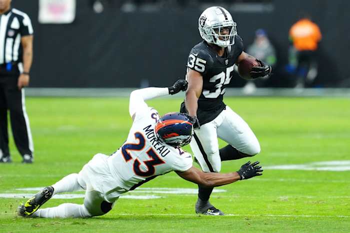Las Vegas Raiders running back Zamir White (35) breaks the tackle of Denver Broncos cornerback Fabian Moreau (23) during the second quarter at Allegiant Stadium.
